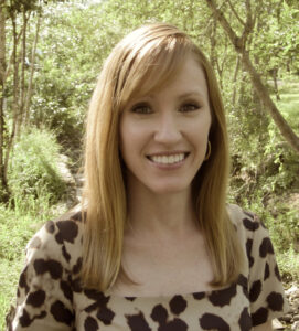 Allison with a leopard print shirt in front of a forested background